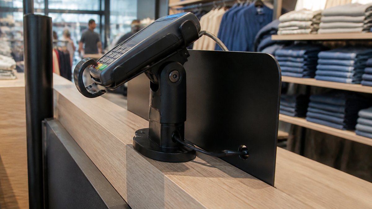POS-Terminal mit Halterung für Sicherheit an einem modernen Kassentisch im Einzelhandel mit geschützter Kabelführung